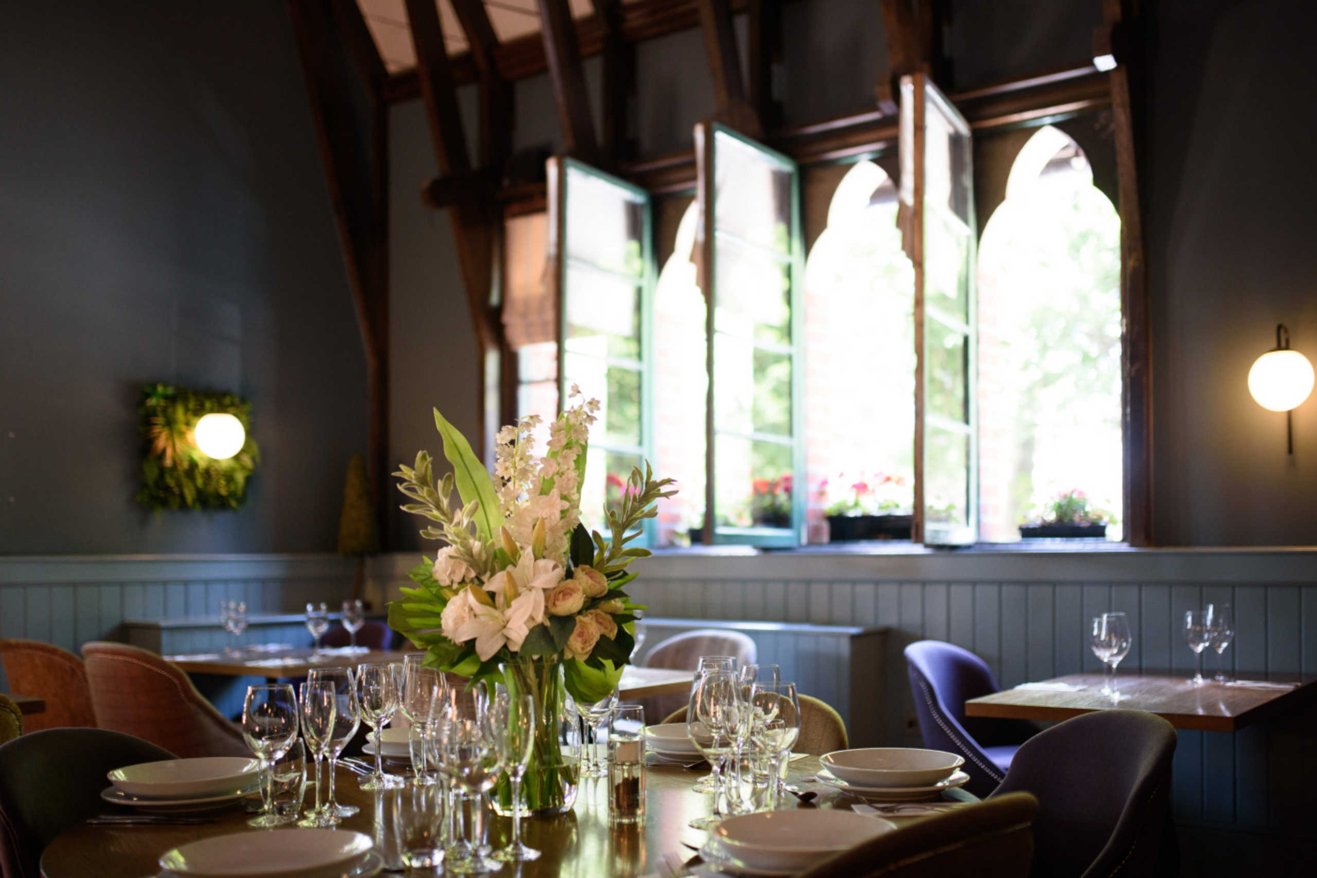 Dining room with arched windows, flower arrangement and window boxes at Schoolhouse Hotel