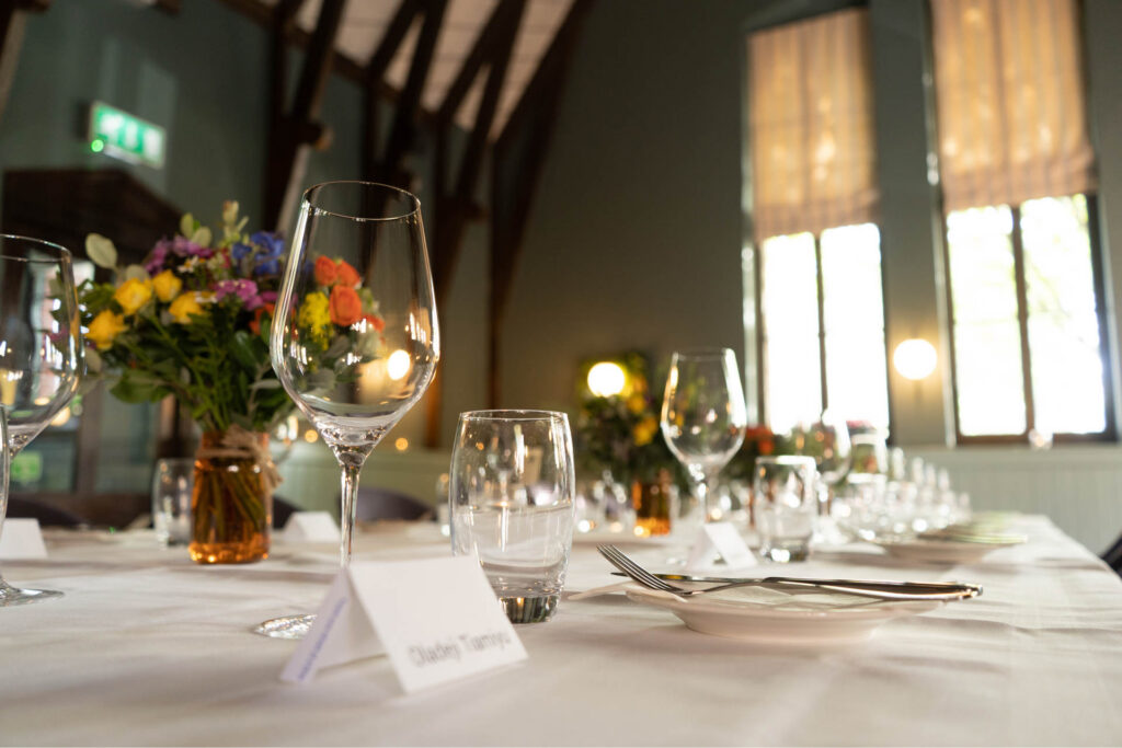 Place setting with a wine glass, place card and bright summer flowers at Schoolhouse Hotel